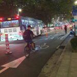 Cyclists ride safely along a protected bike lane separated from car traffic.